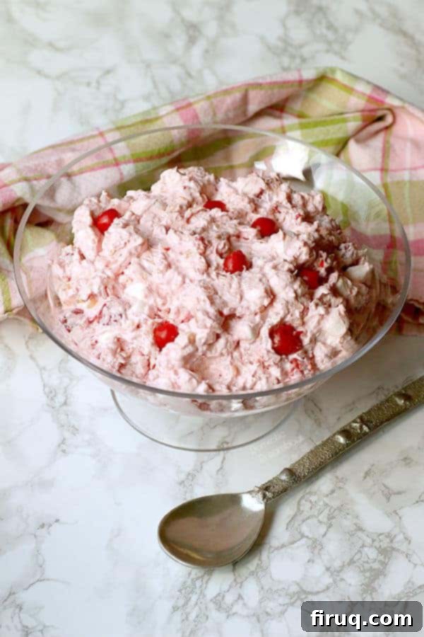 Tropical Cherry Ambrosia Ready to Serve Vibrant pink Tropical Cherry Ambrosia in a glass bowl, garnished with fresh cherries.