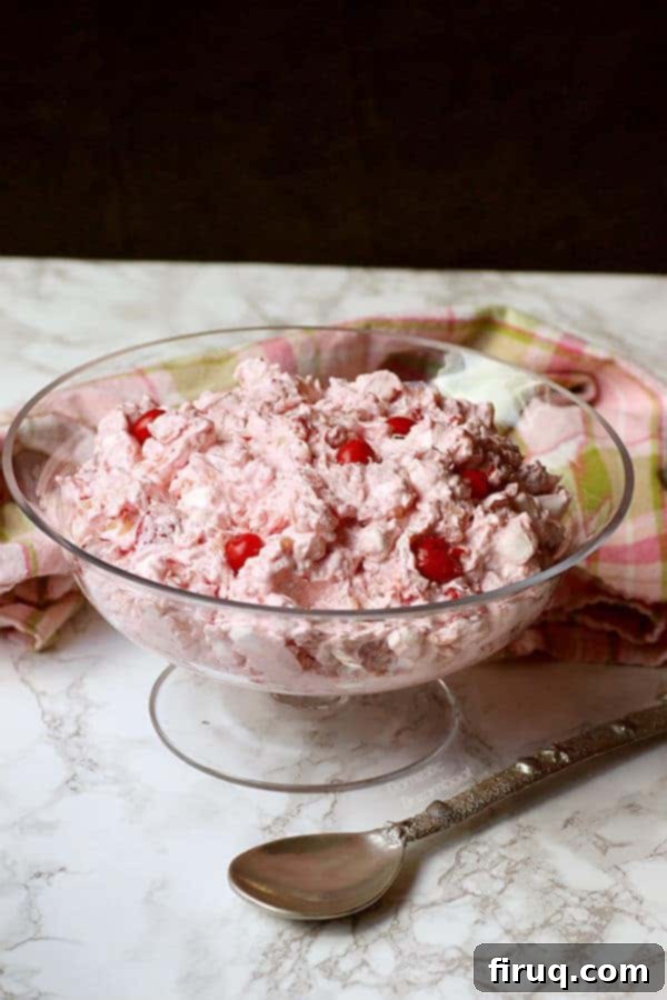 Luscious Cherry Ambrosia Texture Close-up of Tropical Cherry Ambrosia with marshmallows and coconut visible, served in a clear glass bowl.