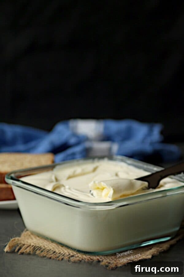 A knife resting in a glass container of homemade spreadable butter. Homemade spreadable butter with knife in glass container