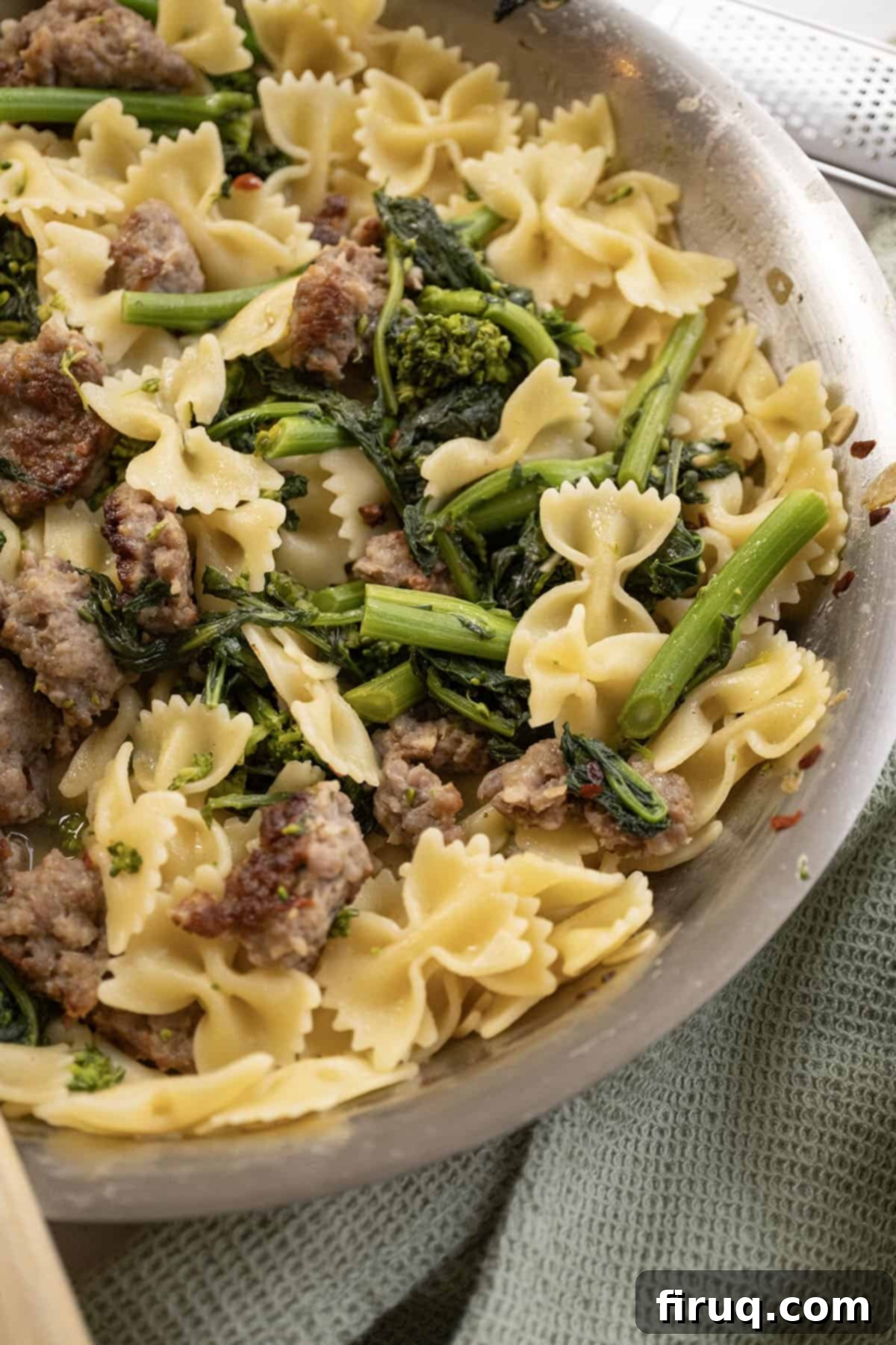 Sausage and Rapini Pasta 12 Farfalle with sausage and broccoli rabe, topped with parmesan on a plate.