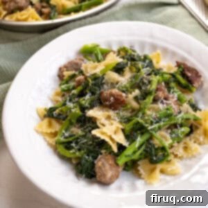 Sausage and Rapini Pasta 13 Farfalle with sausage and broccoli rabe, topped with parmesan on a plate.