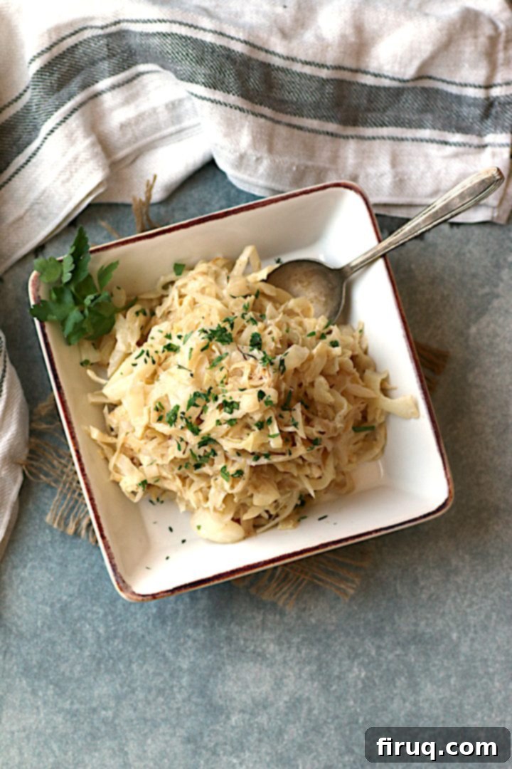 Creamy Caramelized Cabbage Garnished Overhead photo of Creamy Caramelized Cabbage in a square, off-white bowl, freshly garnished with chopped herbs.