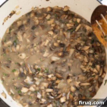 Velvety Mushroom Mascarpone Soup 6 Chicken broth being added to the mushroom mixture in a dutch oven, preparing to simmer.