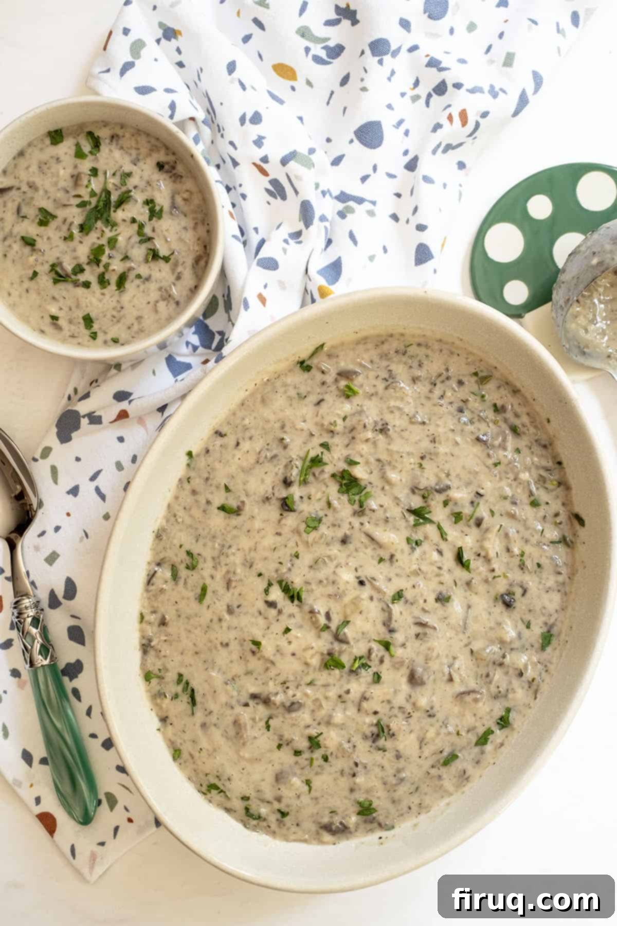 Velvety Mushroom Mascarpone Soup 9 Two bowls of creamy mushroom mascarpone soup, one large serving bowl and a smaller cup, garnished with fresh parsley.
