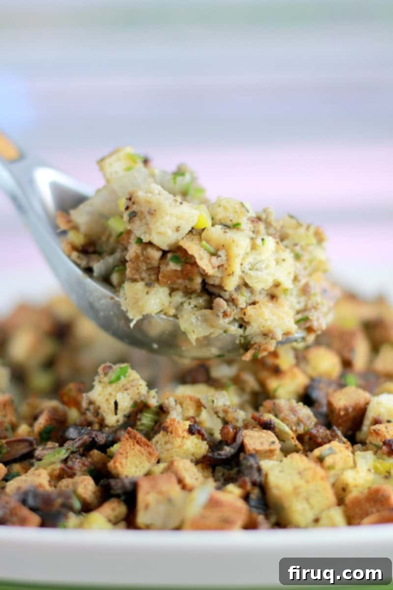 The Ultimate Holiday Stuffing 14 A large silver spoon holding up a scoop of cooked stuffing, showcasing its rich texture