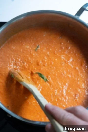 Velvety Red Pepper Sauce 11 Creamy red pepper sauce in a saucepan after heavy cream has been stirred in, showing its beautiful orange-pink hue.