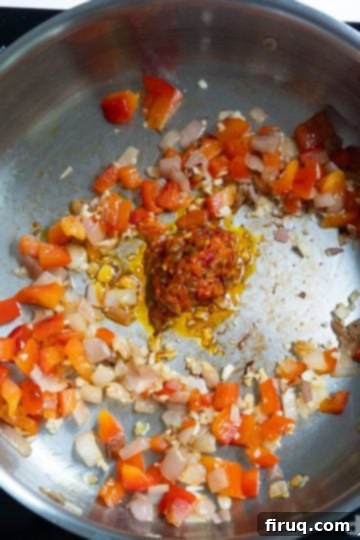 Velvety Red Pepper Sauce 6 Minced garlic and Calabrian chili peppers being added to sautéed shallots and red peppers in a pan.