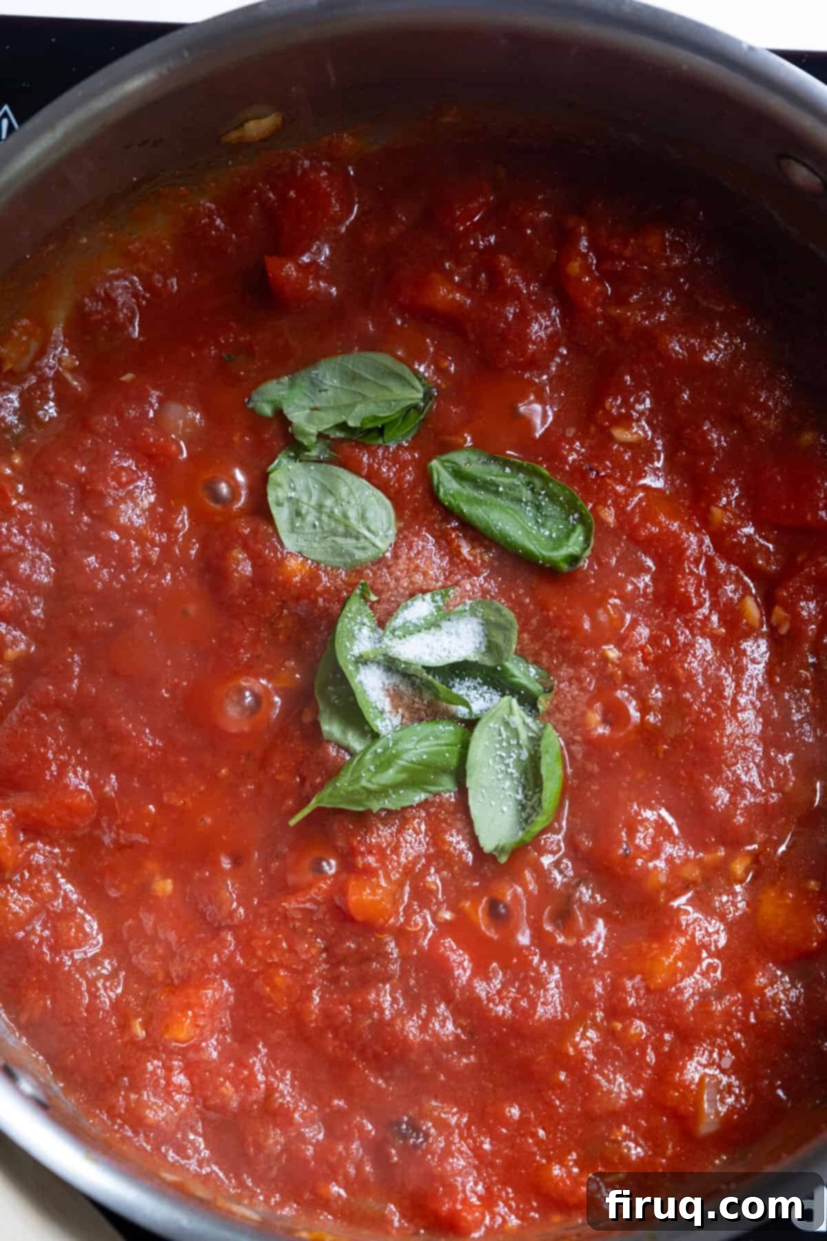 Velvety Red Pepper Sauce 7 Tomato base simmering in a large pan with basil, garlic, and red peppers, creating a rich red sauce.