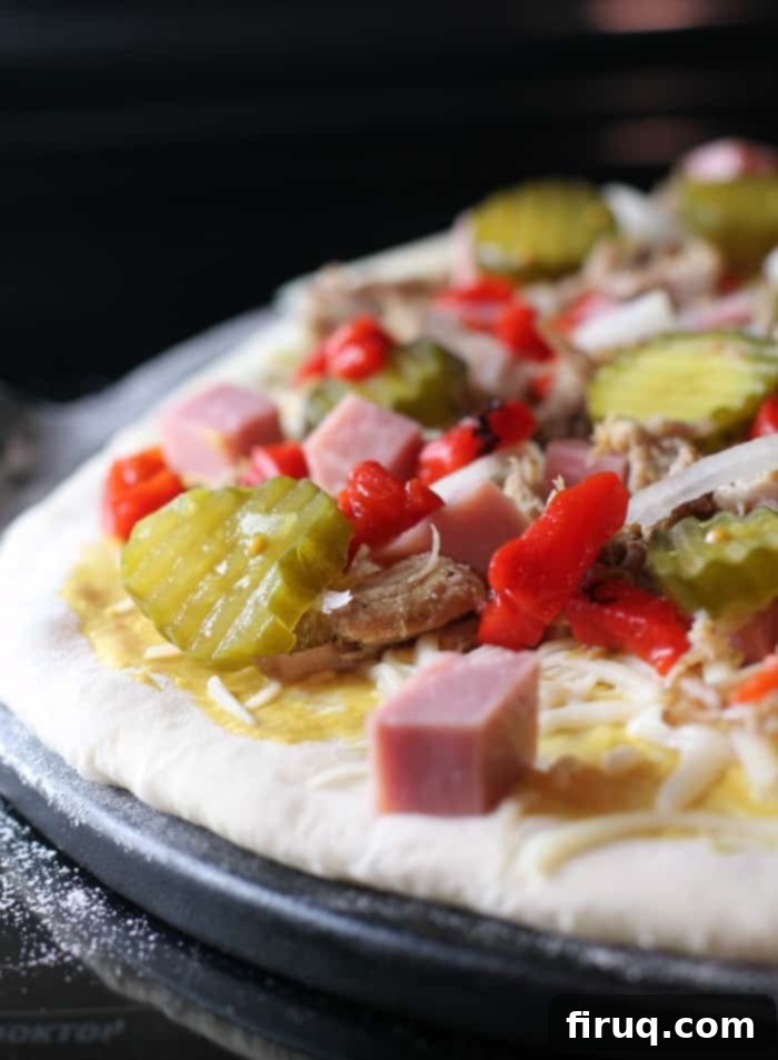 Cuba's Signature Slice 4 Side view displaying abundant toppings on the uncooked Cuban pizza dough, awaiting its final cheese layer.