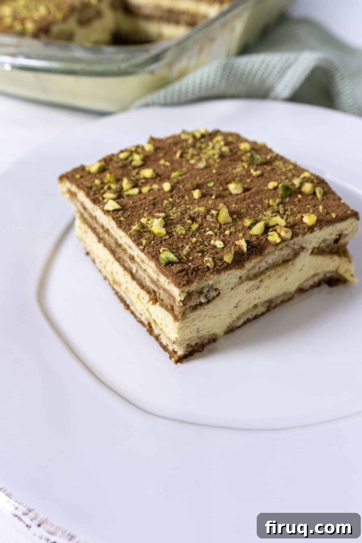 Emerald Dream Tiramisu 14 A beautifully presented slice of Pistachio Cream Tiramisu, garnished with cocoa and pistachios.