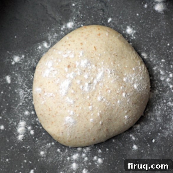 Your Go-To Homemade Pizza Dough 2 A ball of pizza dough with flour sprinkled on top, showcasing its soft and pliable texture