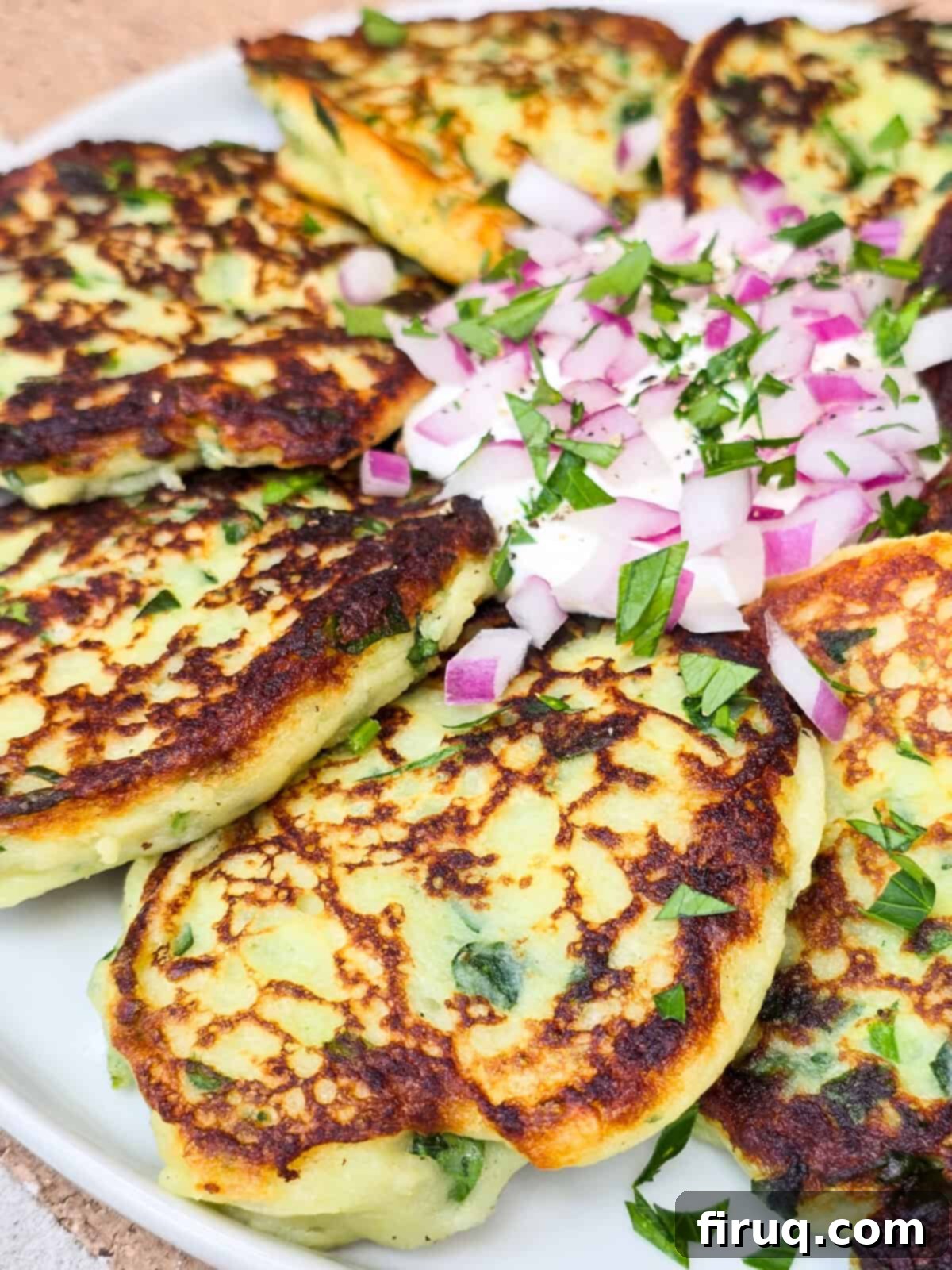 Crispy Garlic Spinach Potato Patties 3 prepared instant mashed potato cakes on plate with sour cream and red onion in the center