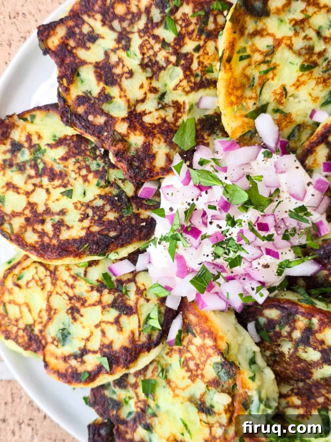 Crispy Garlic Spinach Potato Patties 6 prepared instant mashed potato cakes on plate with sour cream and red onion in the center