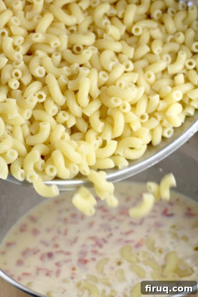 Decadent Crab Mac and Cheese 5 cooked macaroni pouring into bechamel sauce