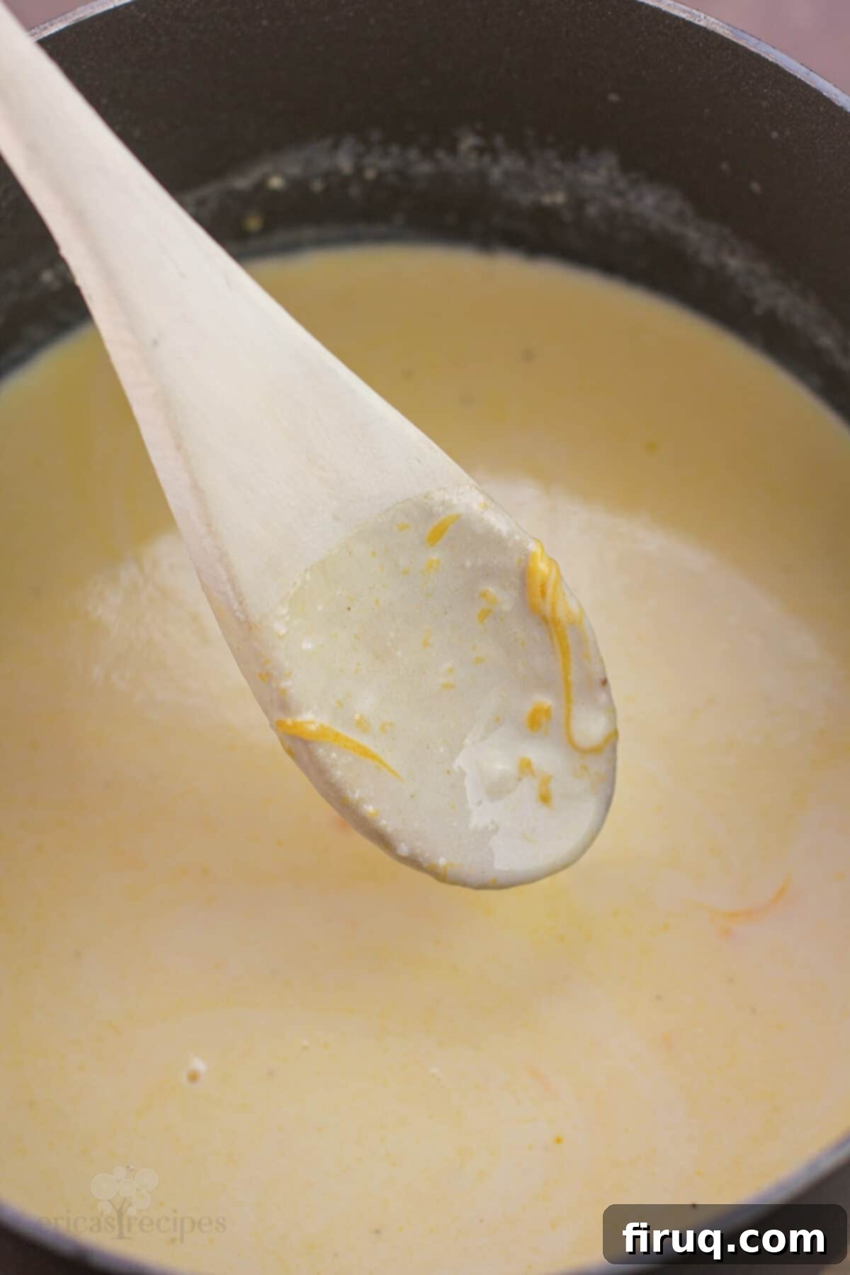 Classic Velvety Mac and Cheese 11 spoon with sauce on it and bits of cheese