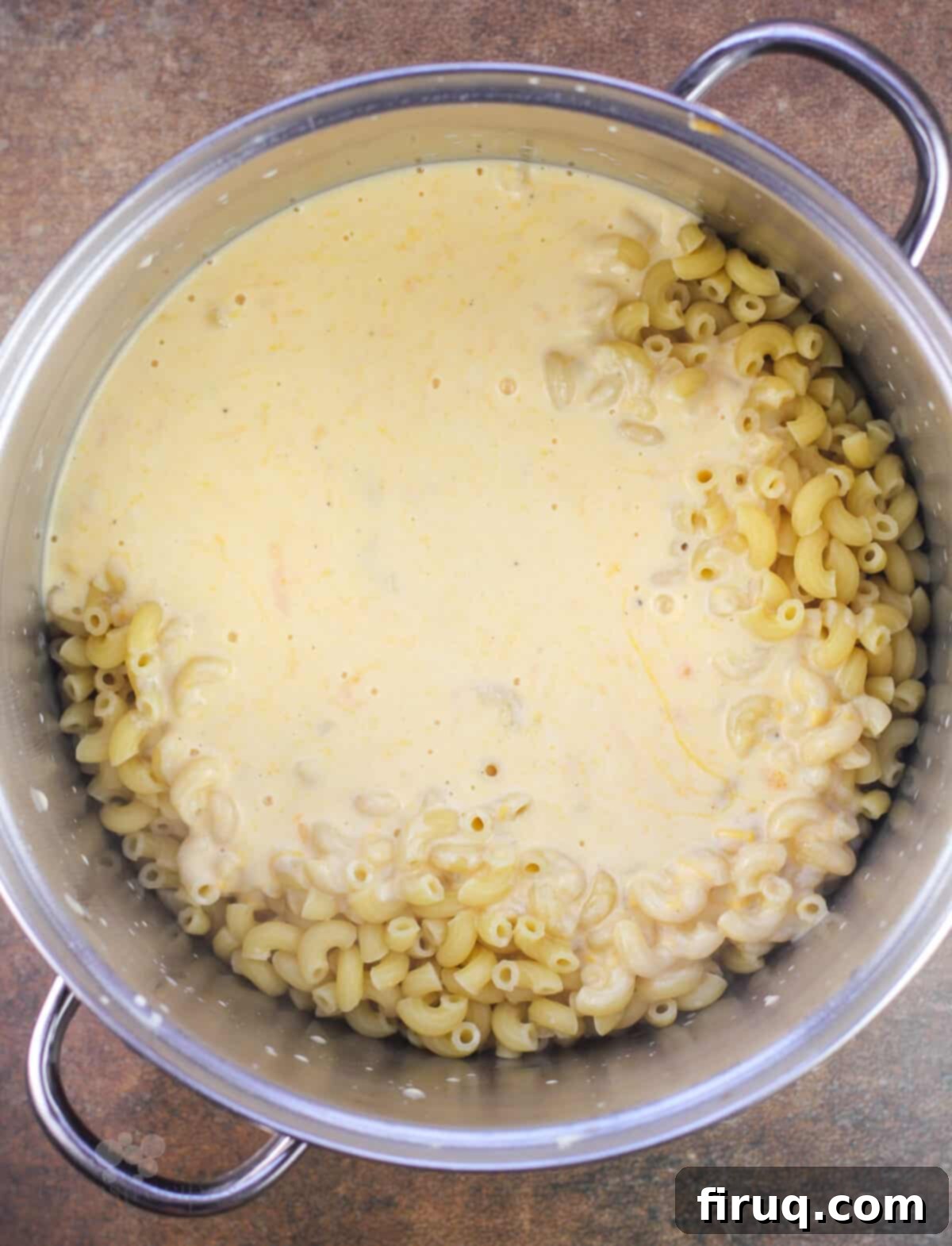 Classic Velvety Mac and Cheese 12 cheese sauce added to macaroni in metal pot