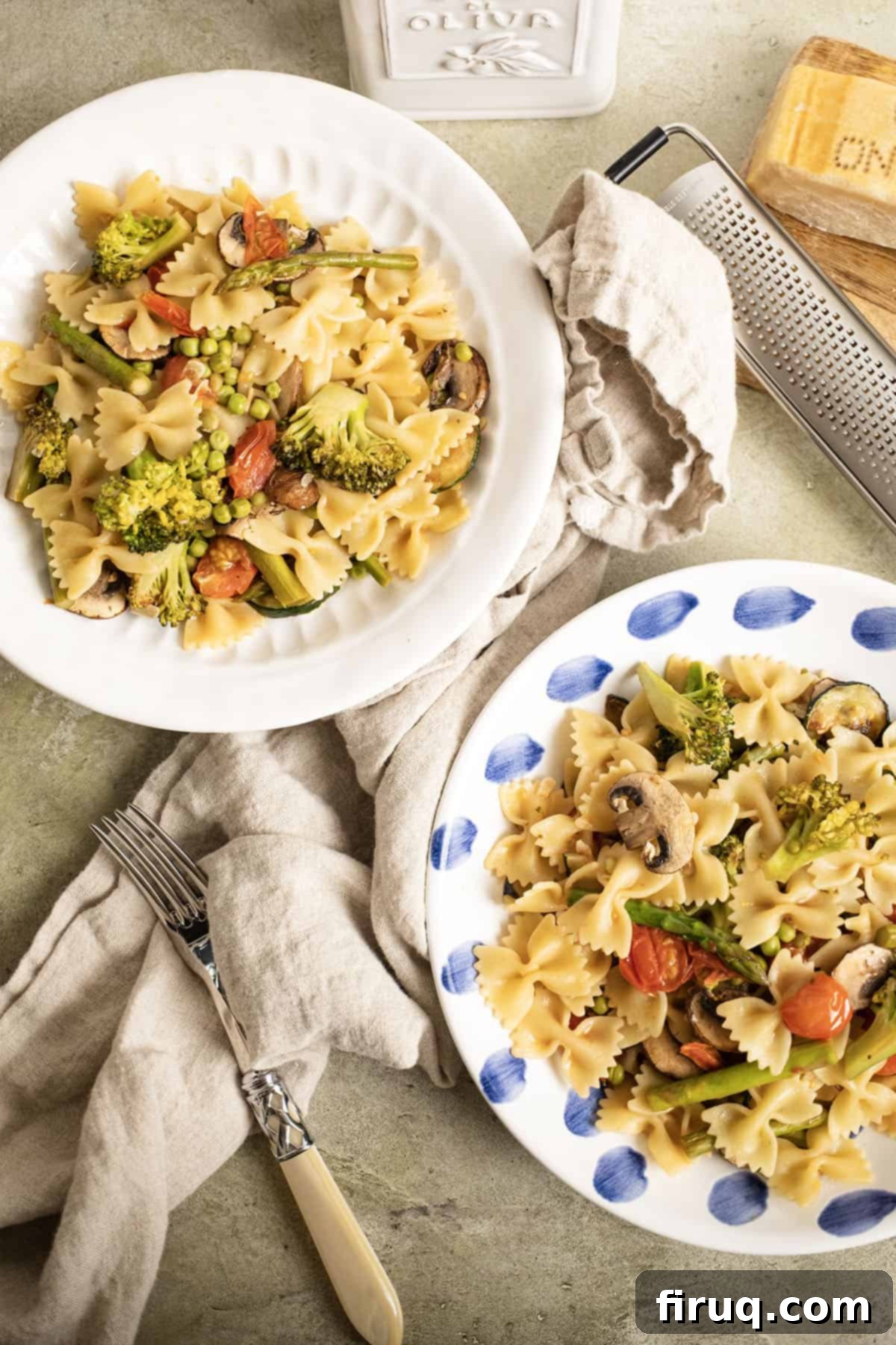 Broccoli and Asparagus Pasta Primavera 10 Two bowls filled with vibrant pasta primavera, accompanied by a small bowl of parmesan cheese.