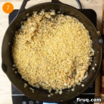 One-Pan Cast Iron Lemon Chicken Orzo 7 Orzo added to the pan and combined with onions and garlic.