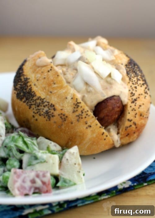 Beer-Glazed Kielbasa and Sausage with Stout Queso 8 angled view of the finished Grilled Beer Kielbasa with Sausage and Stout Queso, topped with onions, on a white place with a bit of salad on the side