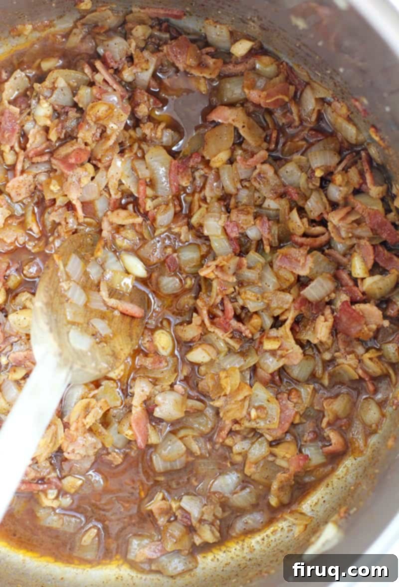 Cowboy Style Mexican Beans 5 bacon, onion, garlic, and jalapeno cooking in a pot stirred with a wooden spoon