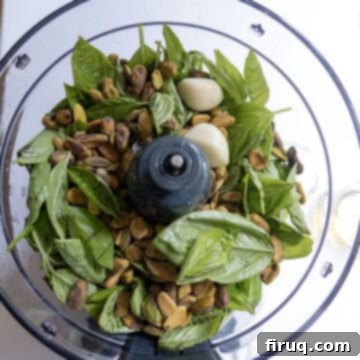 Perfect Pesto Stuffed Chicken 4 Ingredients for pistachio pea pesto in a food processor, including fresh peas, basil, garlic, and pistachios, ready to be blended into a smooth sauce.