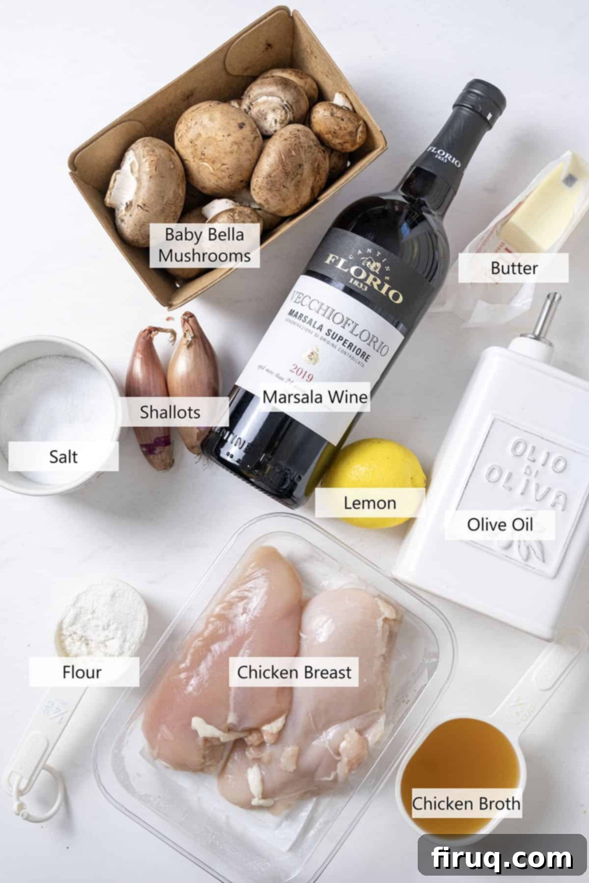 Rich Marsala Chicken with Sautéed Mushrooms 3 A flat lay of fresh ingredients for chicken marsala including chicken breasts, mushrooms, shallots, lemon, and a bottle of Marsala wine.