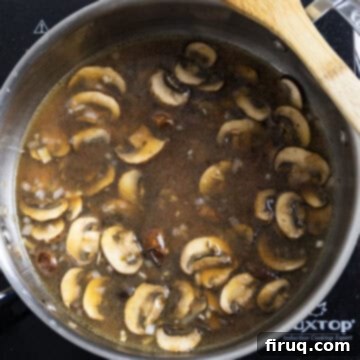 Rich Marsala Chicken with Sautéed Mushrooms 8 Marsala wine and chicken broth being poured into the pan with sautéed mushrooms and shallots, ready for simmering.