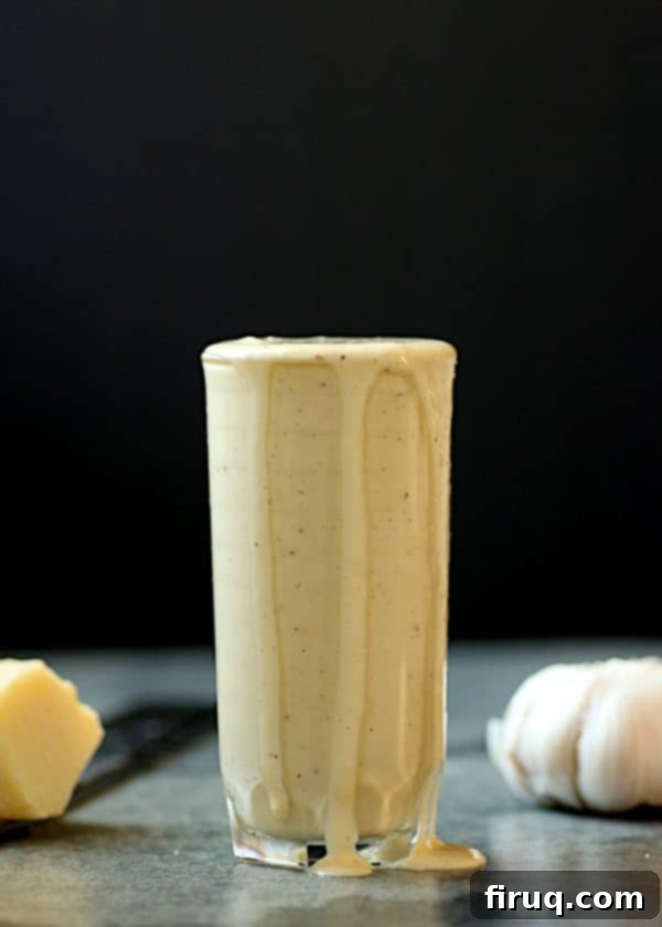Creamy Homemade Caesar Dressing A glass filled to the brim with homemade caesar salad dressing, showcasing its creamy texture.