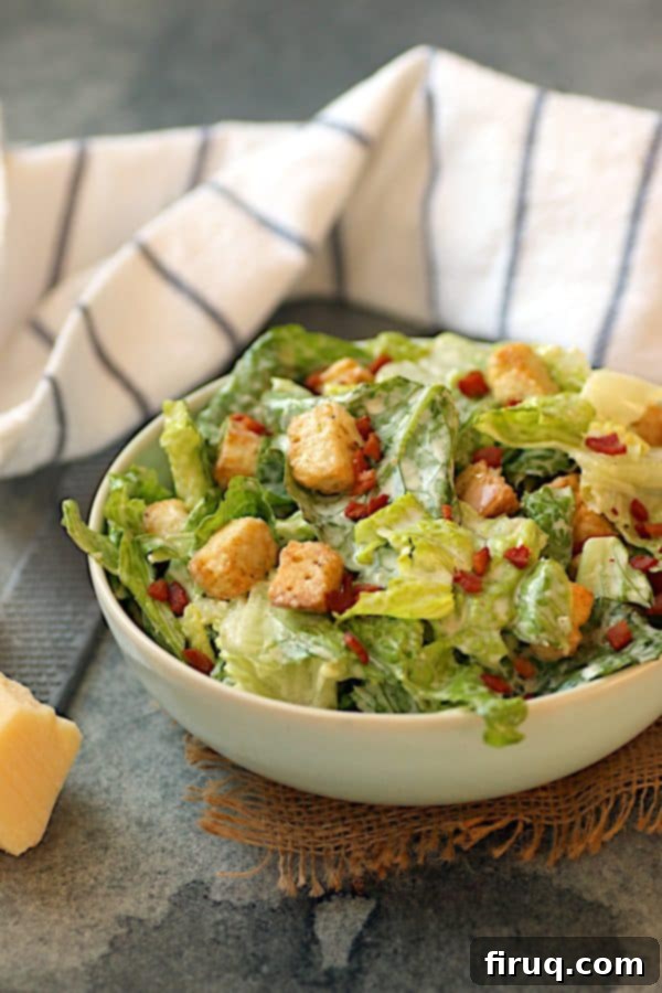 Delicious Caesar Salad with Bacon Freshly tossed Caesar salad with crispy bacon bits in a pale blue bowl, ready to be served.