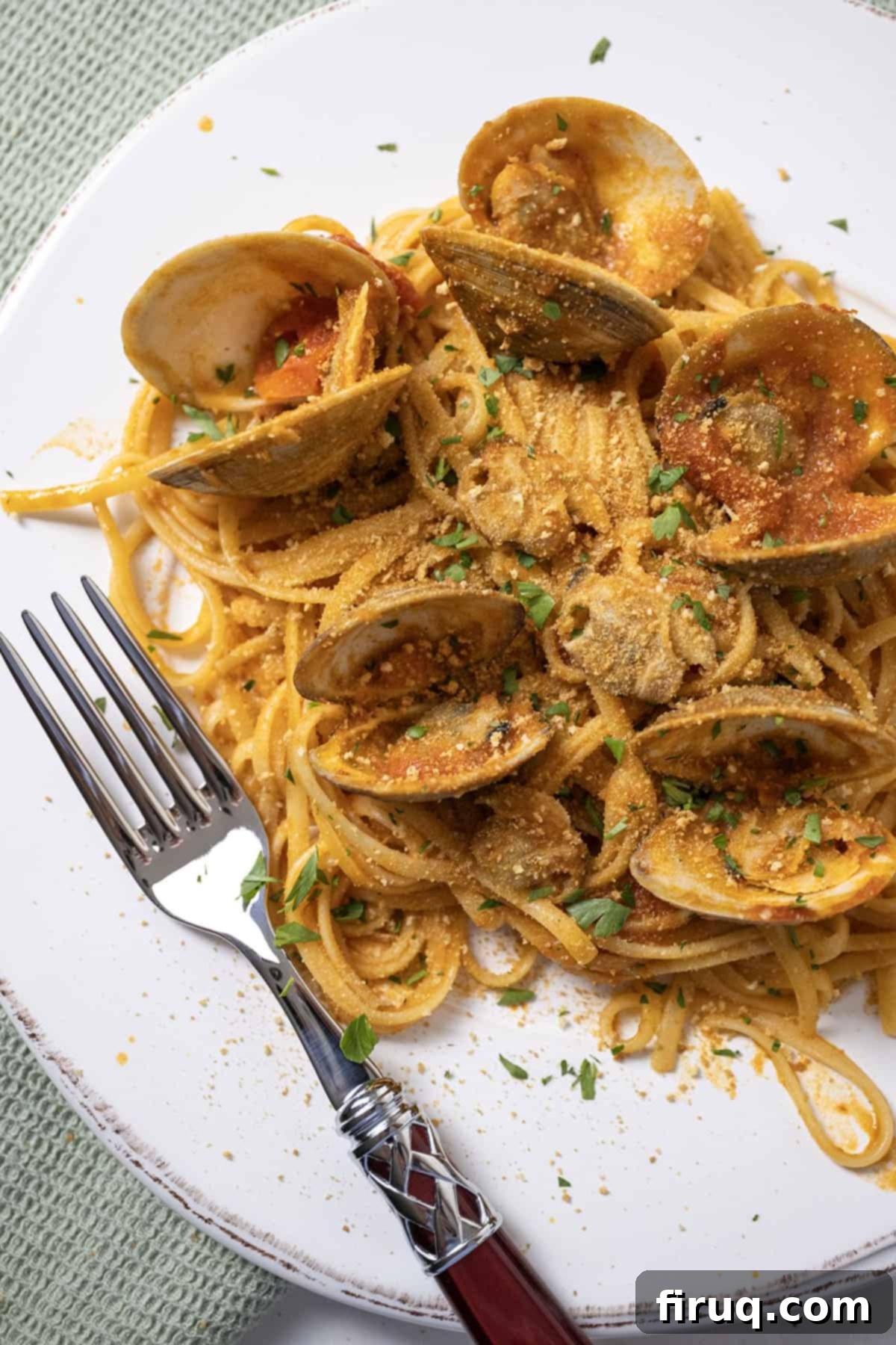 Robust Red Clam Linguine 2 A beautifully plated dish of linguine with clams in a rich red sauce, garnished with fresh herbs and toasted breadcrumbs.