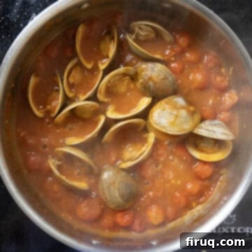 Robust Red Clam Linguine 9 Opened clams mingling with the rich red sauce in a saucepan, pasta water added for consistency.
