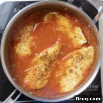 Ultimate Chicken Pizzaiola 10 Golden-brown chicken cutlets carefully placed into the simmering tomato sauce, ready to braise.