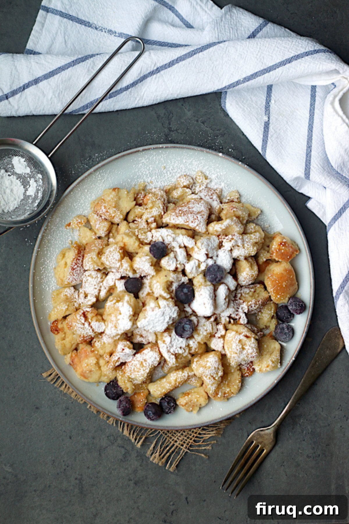 Kaiserschmarrn with Blueberries and Powdered Sugar Overhead photo of Austrian Shredded Pancake with blueberries and powdered sugar on a plate.