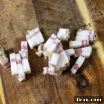 Bucatini Amatriciana 5 Guanciale meticulously chopped into strips on a wooden cutting board.