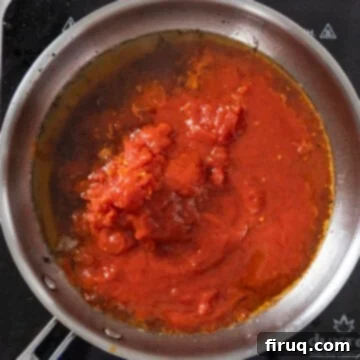 Bucatini Amatriciana 8 Whole peeled plum tomatoes being hand-squeezed into the rendered guanciale oil in a saucepan, starting the sauce base.