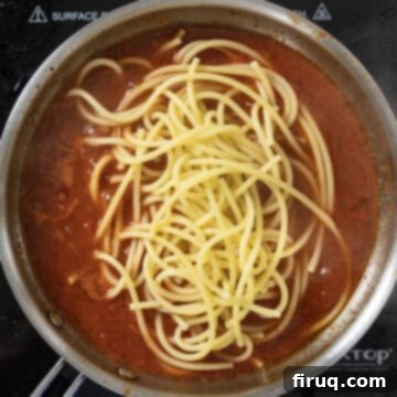 Bucatini Amatriciana 10 Al dente bucatini pasta being tossed directly into the simmering red sauce in a saucepan.