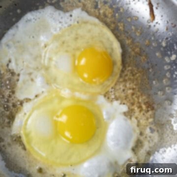 Your Italian Breakfast Sandwich 11 Eggs cooking on top of the crispy parmesan cheese in a pan.