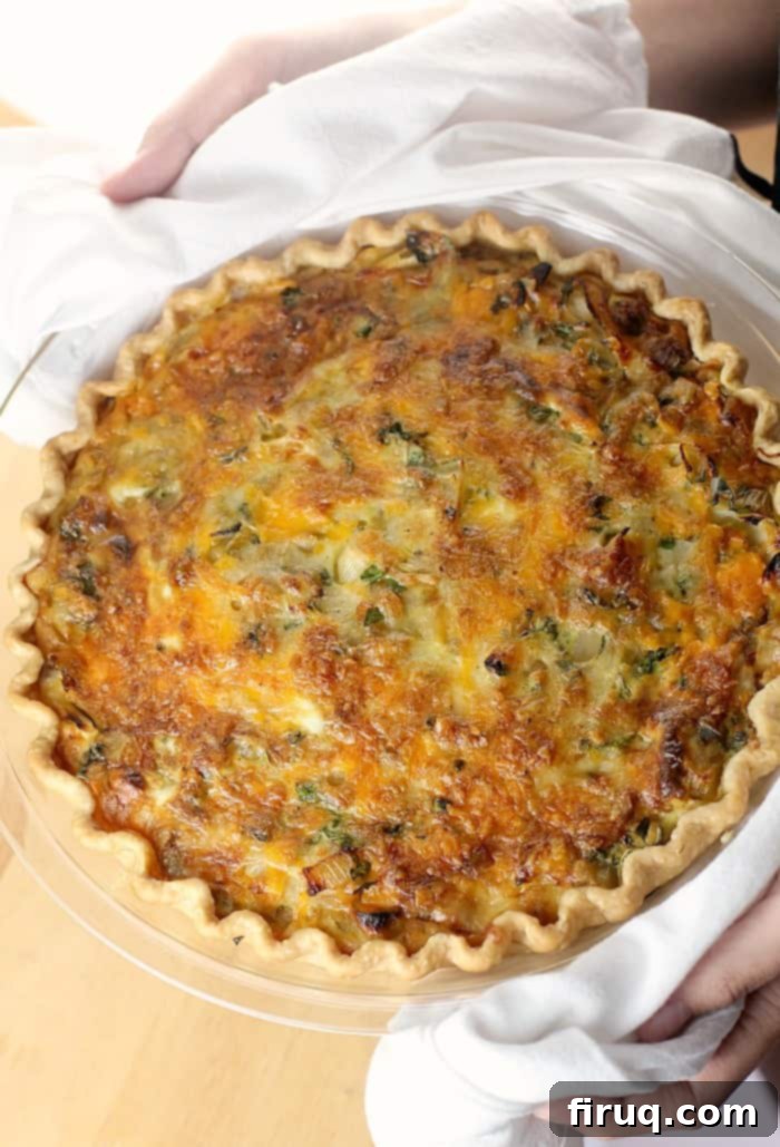 Savory Sausage and Sweet Onion Quiche 2 hands holding cooked quiche in white dish towel