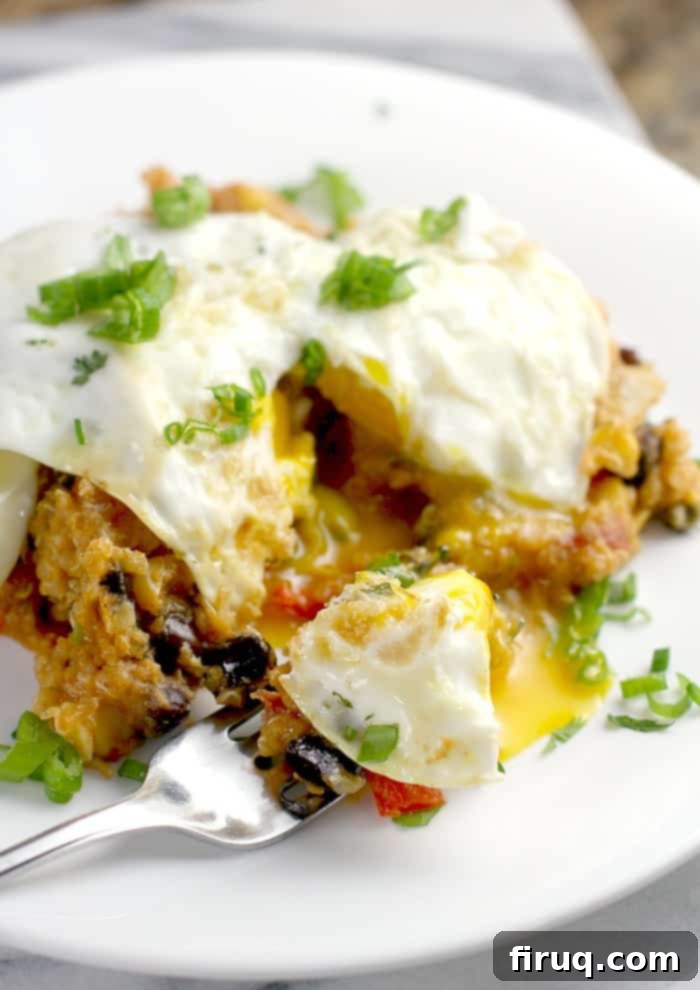 Set-It-And-Forget-It Quinoa Tamale Casserole 3 over easy egg on serving of tamale casserole on white plate with fork