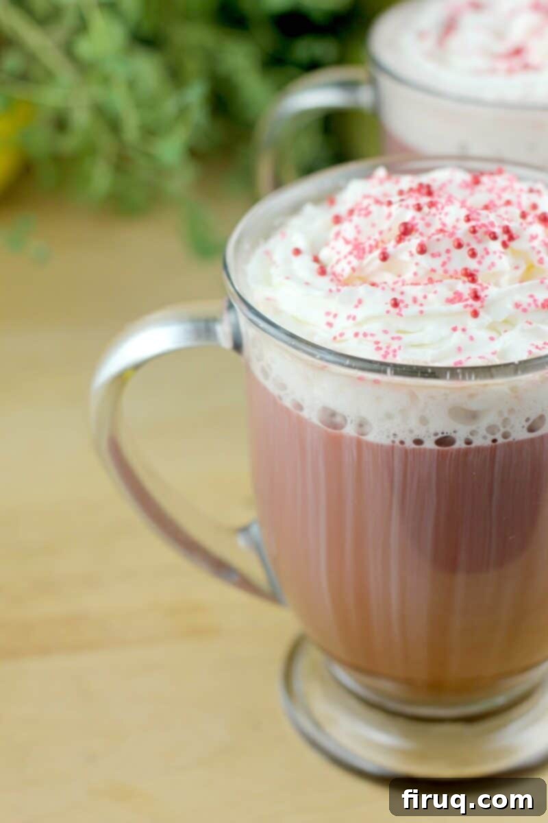 Red Velvet Latte 11 A side view of a glass mug filled with Red Velvet Latte, showcasing its rich red color and creamy texture before any toppings are added.