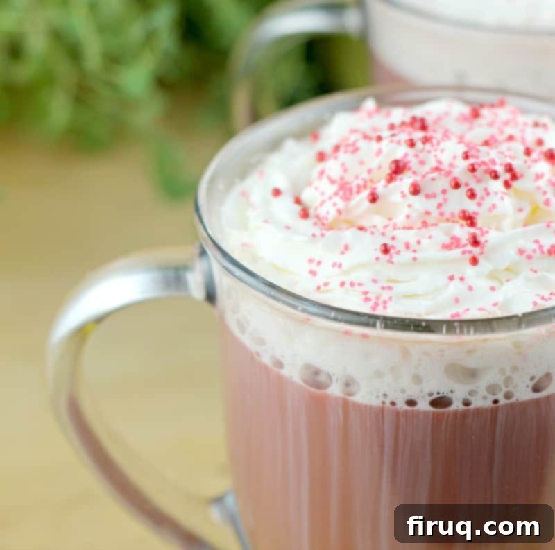 Red Velvet Latte 3 Close-up view of a Red Velvet Latte topped with fluffy whipped cream and vibrant red sugar sprinkles, showcasing its decadent appearance.