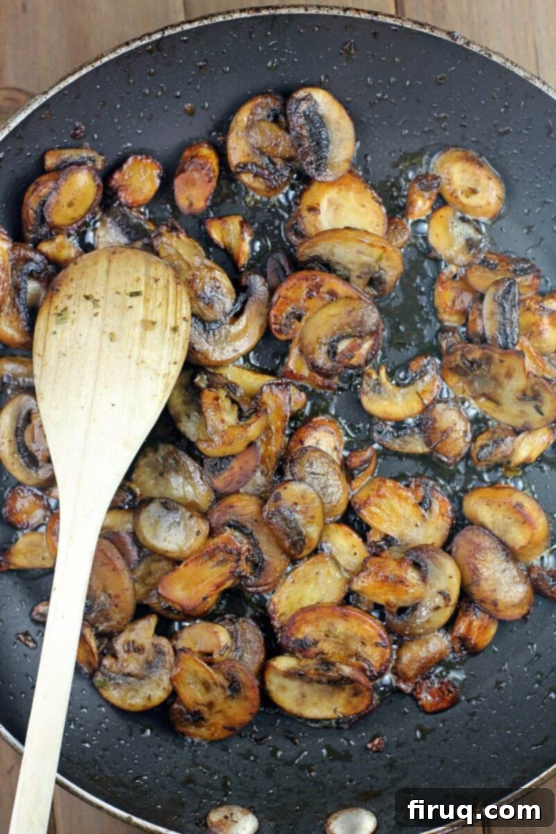 Sauté Mushrooms to Golden Perfection 2 mushrooms in a skillet with wood spoon
