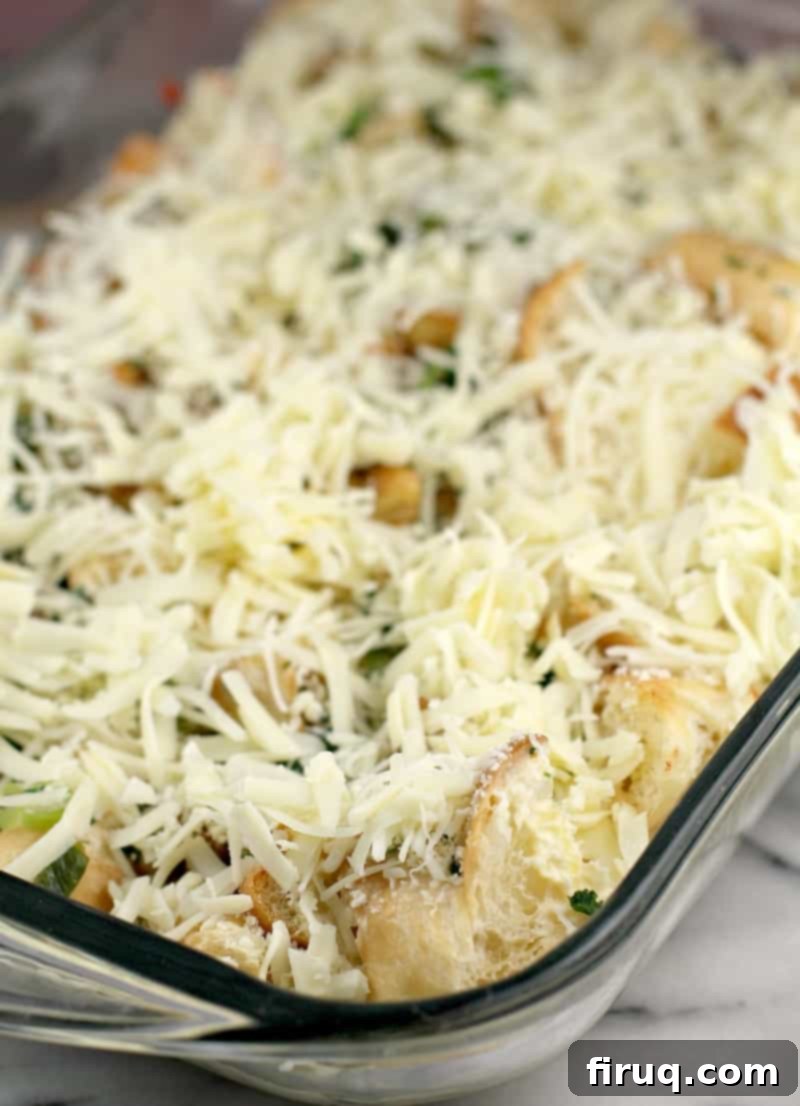 Christmas Morning Croissant Bake 8 assembled casserole in clear glass bake dish topped with cheese prior to refrigeration and baking