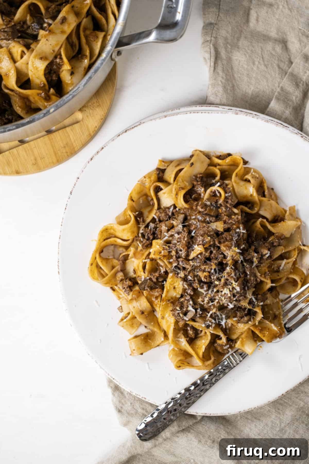 Effortless Lamb Ragu with Pappardelle 12 Lamb ragu over pappardelle on a small plate with pan with pasta next to it.