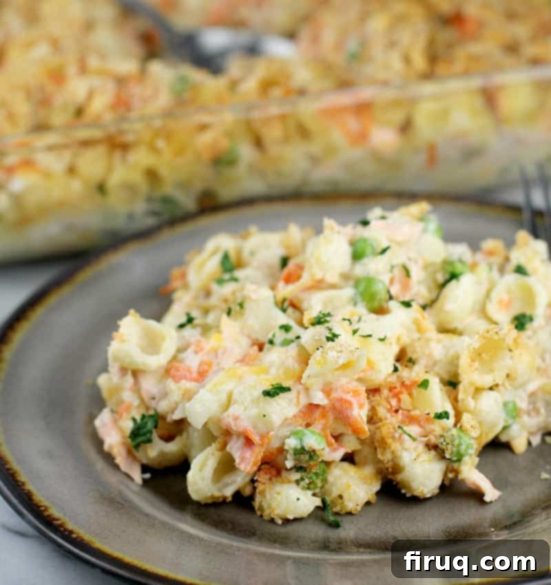 Golden Salmon Casserole 2 Cooked fresh salmon casserole in a serving dish, with the main baking dish blurred in the background, showcasing its golden-brown topping