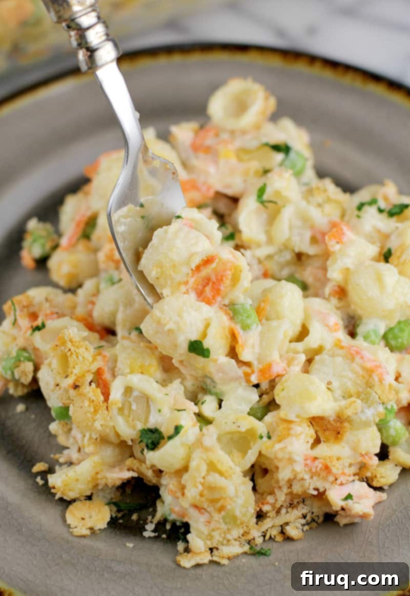 Golden Salmon Casserole 11 Serving of cooked fresh salmon casserole on a plate, with a fork scooping a portion from the center, showing creamy texture