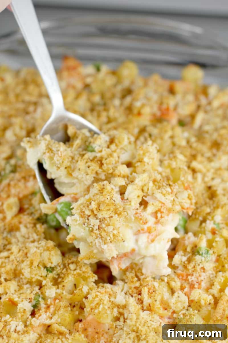 Golden Salmon Casserole 12 Close-up of cooked fresh salmon casserole in a baking dish, with a large serving spoon scooping out a portion, showing the creamy interior