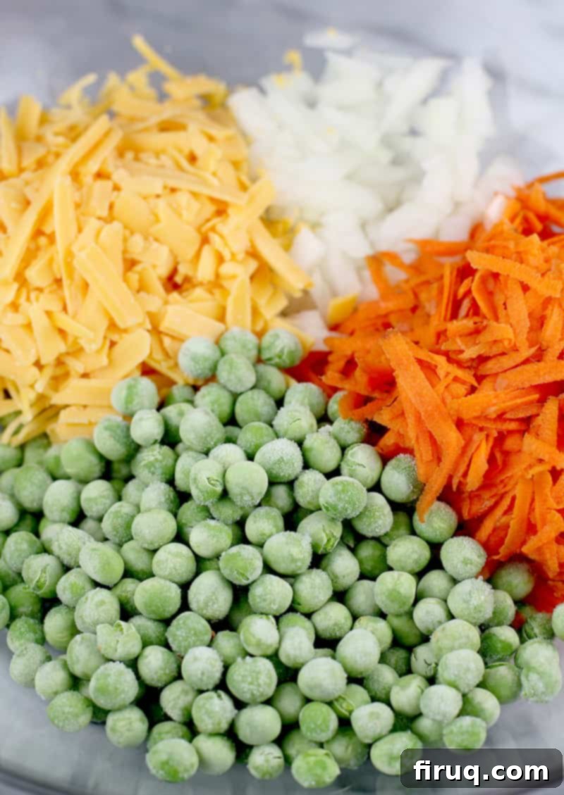 Golden Salmon Casserole 6 Bowl containing a mix of peas, shredded cheddar cheese, diced onion, and shredded carrots, ready for the casserole mixture