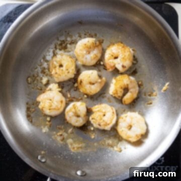 Velvety Pesto Shrimp Pasta 6 Searing shrimp in a stainless steel pan.