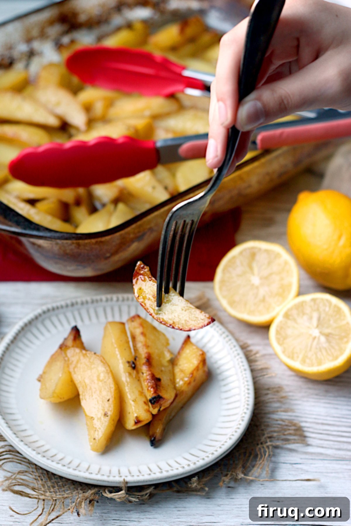 Enjoying Greek Lemon Potatoes A fork picking up a Greek Lemon Potato from a small white plate.